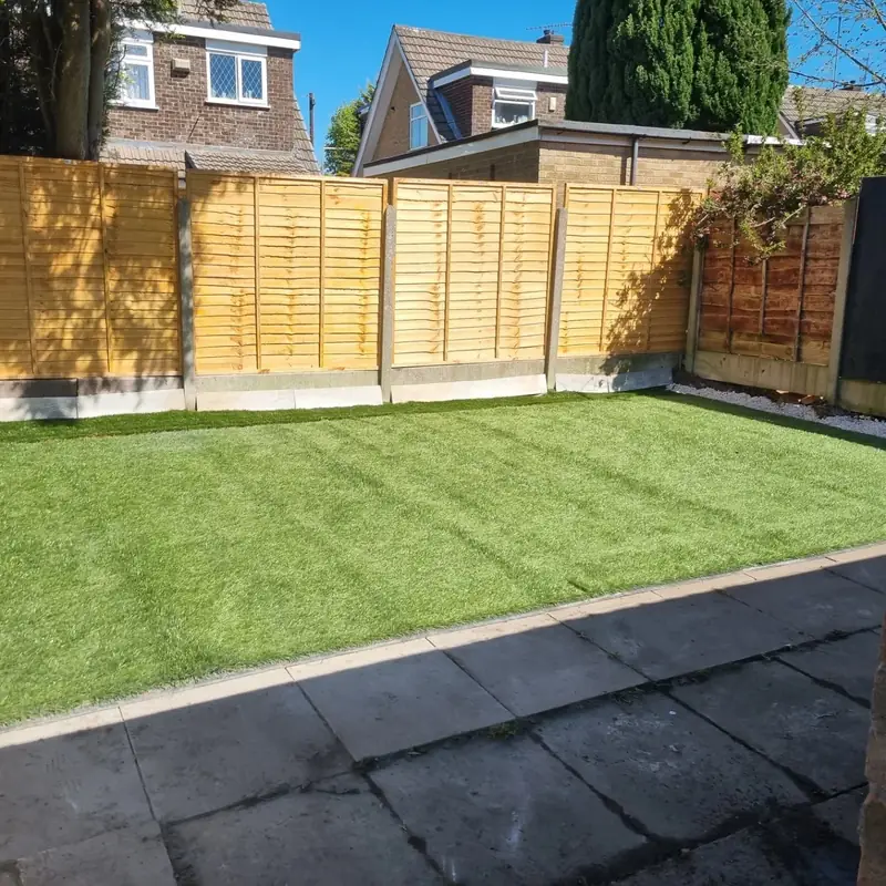 Finished garden with artificial grass in front of new overlap fence panels on concrete posts