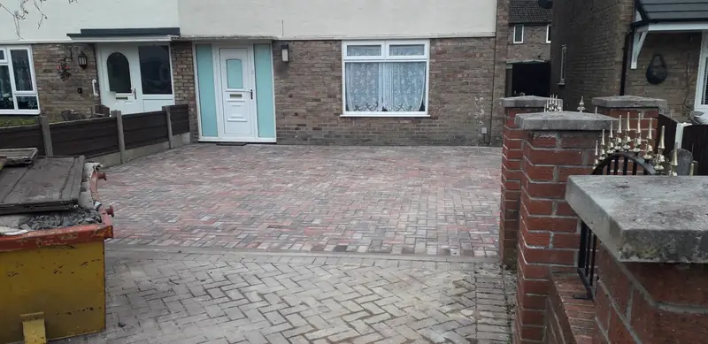 New block paving driveway in red and brindle blocks laid in herringbone up to the front door, with brick gate piers