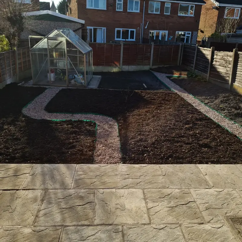 Finished back garden remodel with a riven patio, a winding gravel path and fresh soil beds ready for planting