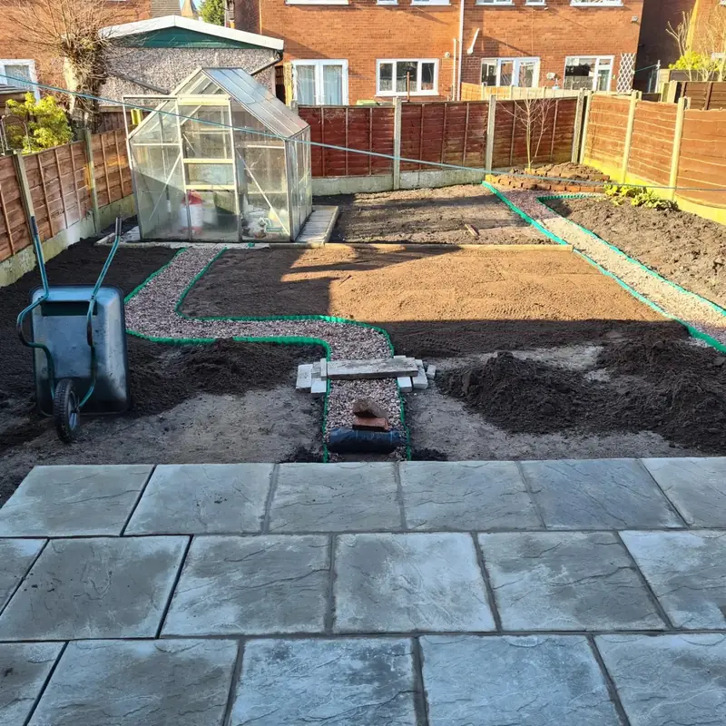 Curved gravel path with green edging running through new soil beds from a riven slab patio
