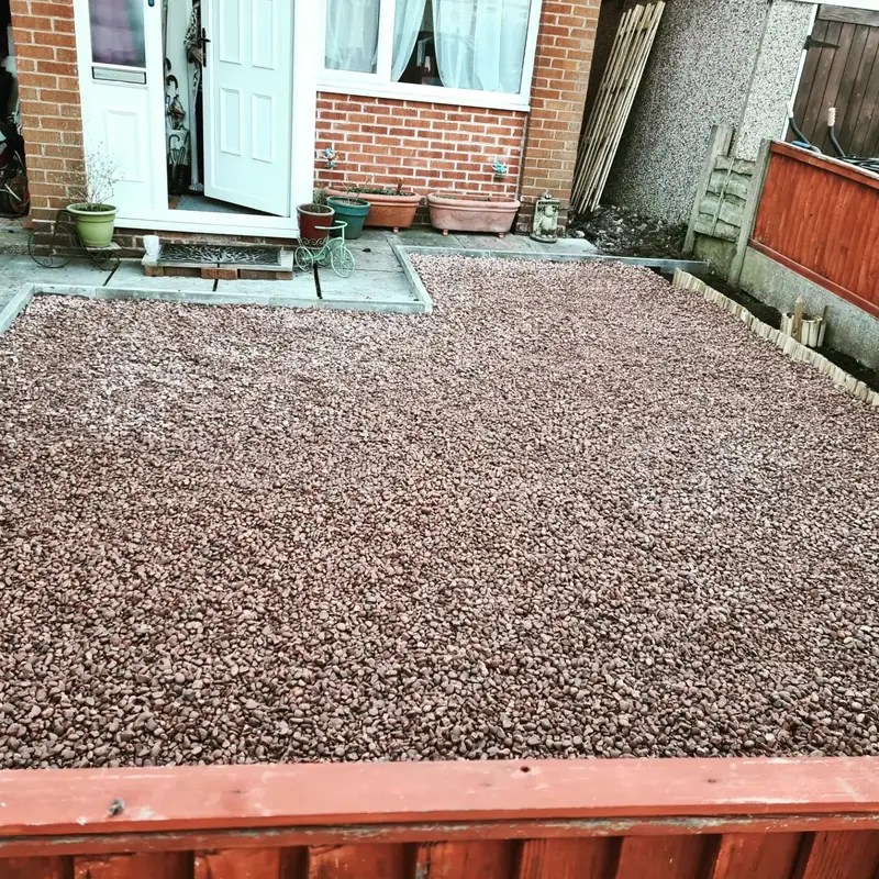 Finished low maintenance garden covered in fresh red gravel up to a timber edge