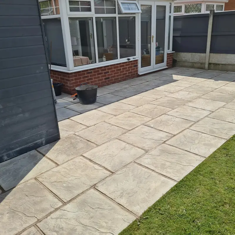 Grey riven paving slabs laid along a lawn in front of a conservatory
