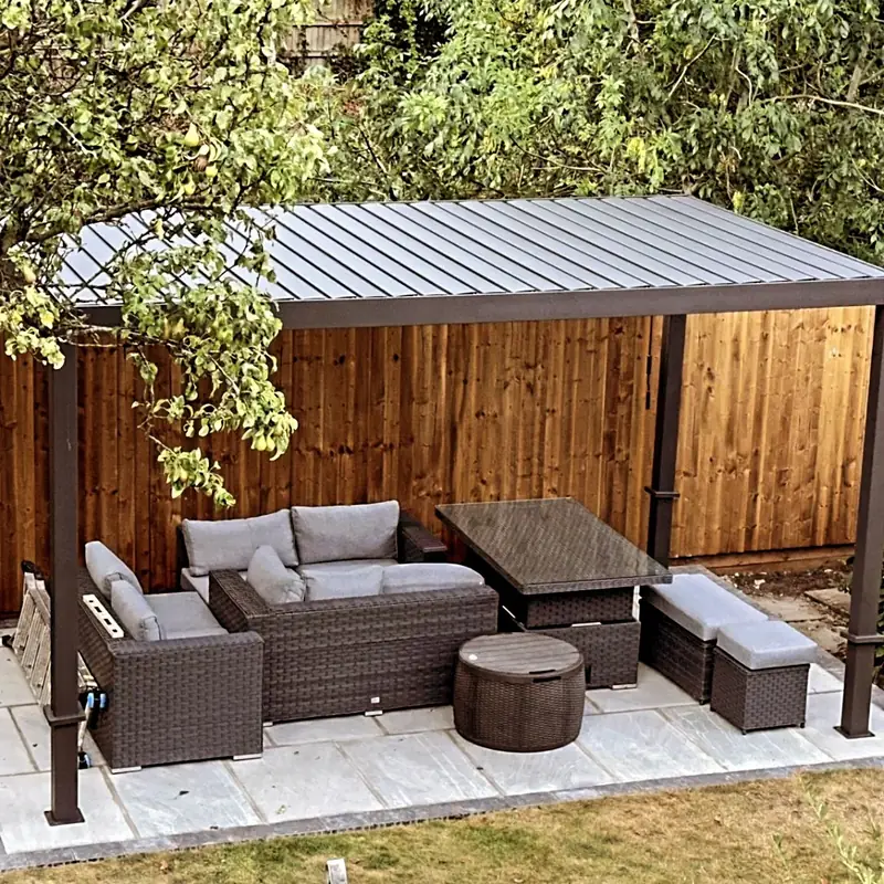 The same grey patio finished and in use, with a gazebo and garden furniture against the new fence